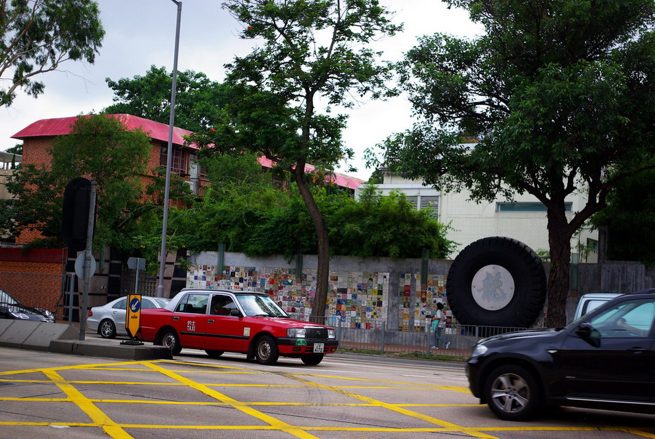 马路对面是成龙大哥影迷搞的一面墙，请注意最左边等车的那辆：Ferrari